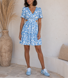 Robe courte florale bleu ciel avec décolleté V, dos légèrement ouvert et ouvertures sur les côtés