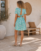    Robe courte florale vert d’eau en polyester avec décolleté V, dos ouvert et ouvertures sur les côtés